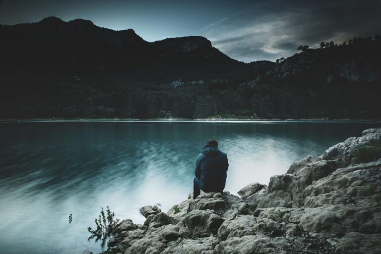 alone-man-sitting-near-river-